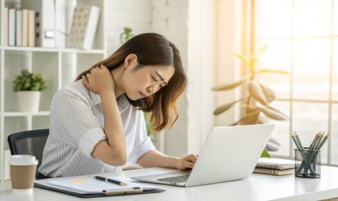 デスクワーク女性と肩こり 「PC作業で肩を押さえてつらそうにしている女性」