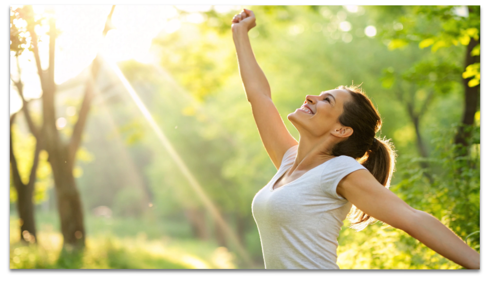朝の光の中で気持ちよくストレッチをする女性。デトックスで心身がすっきり整ったイメージ。
