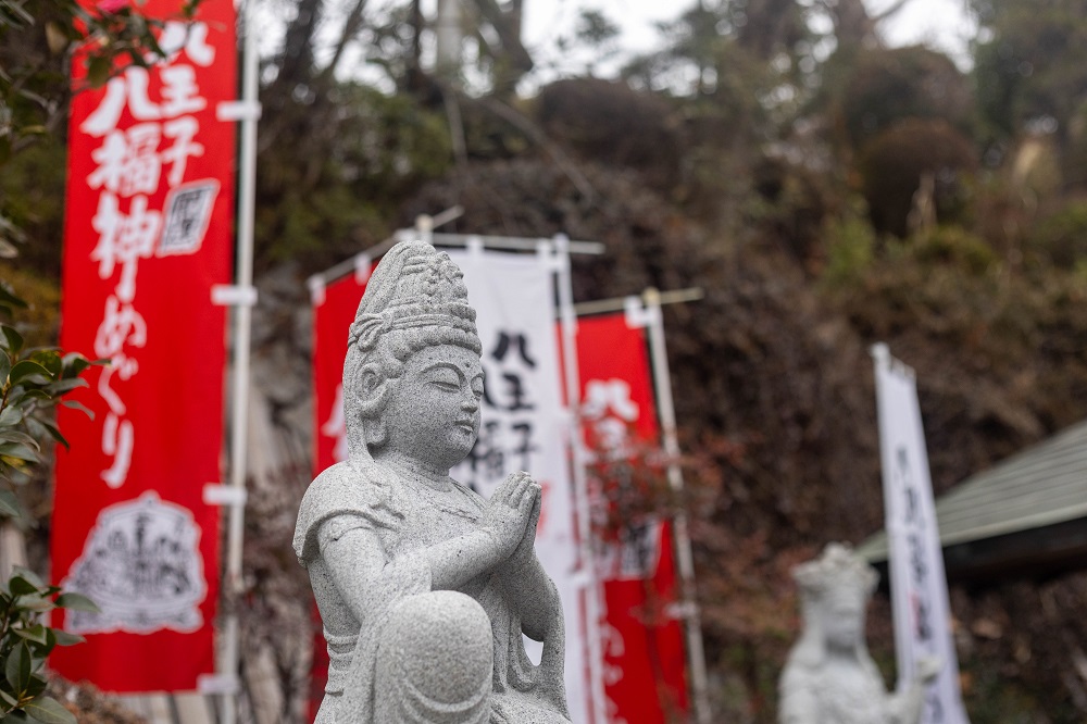 八王子は七福神ならぬ“八”福神?新年の開運散歩と、歩き疲れた足のケア 9 八王子八福神めぐりの赤いのぼり旗と、穏やかな表情で佇む石像